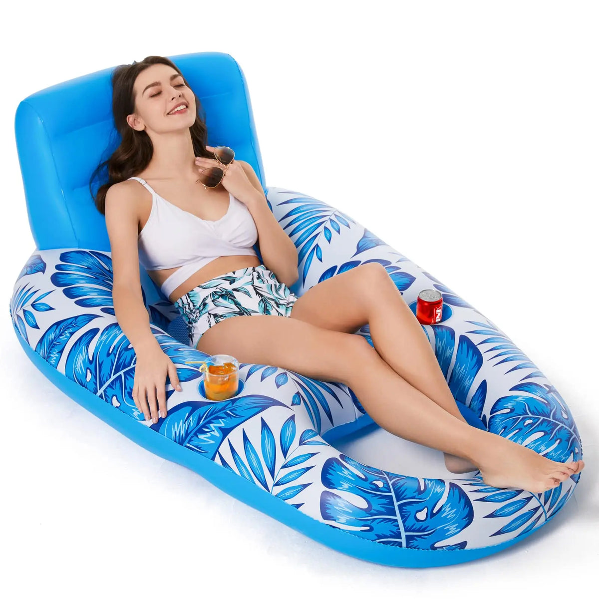 Woman reclining on a blue and white leaf-print inflatable lounger with a drink in the cup holder
