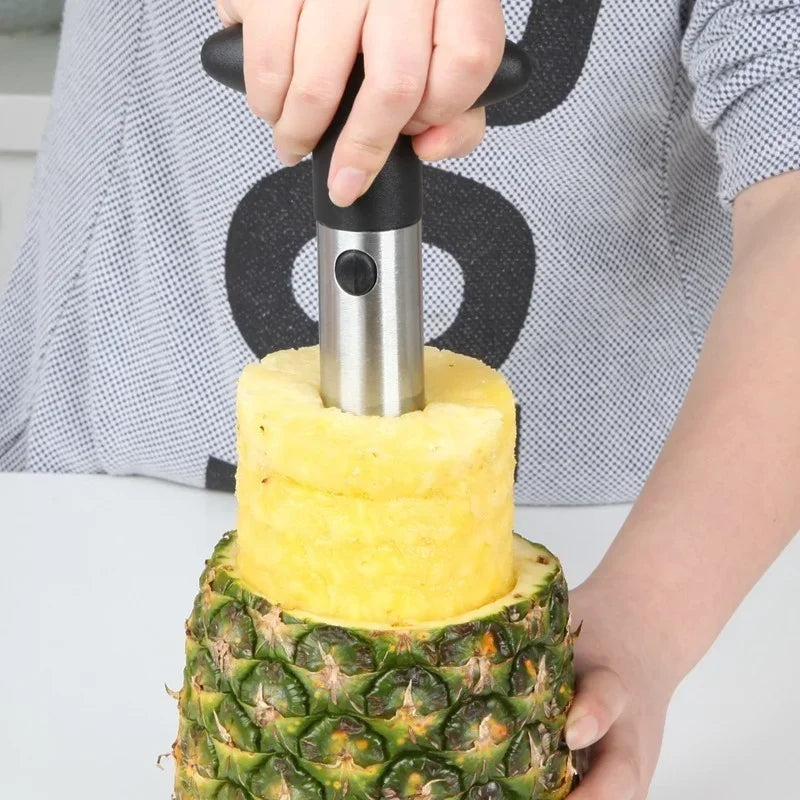 Person pressing the corer down into a pineapple on a white worktop