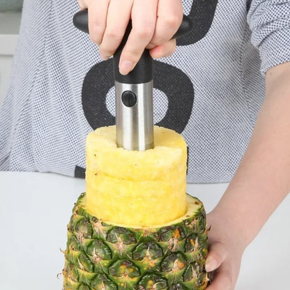 Person pressing the corer down into a pineapple on a white worktop